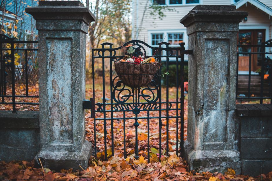 A stone gate pillar with a gate leading to a house.