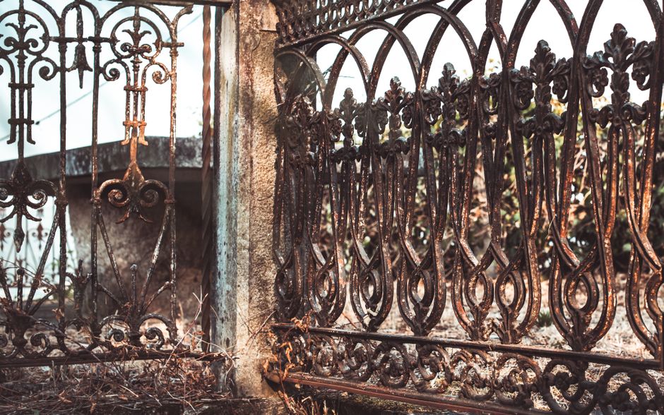 A weathered iron fence with decorative scrollwork.